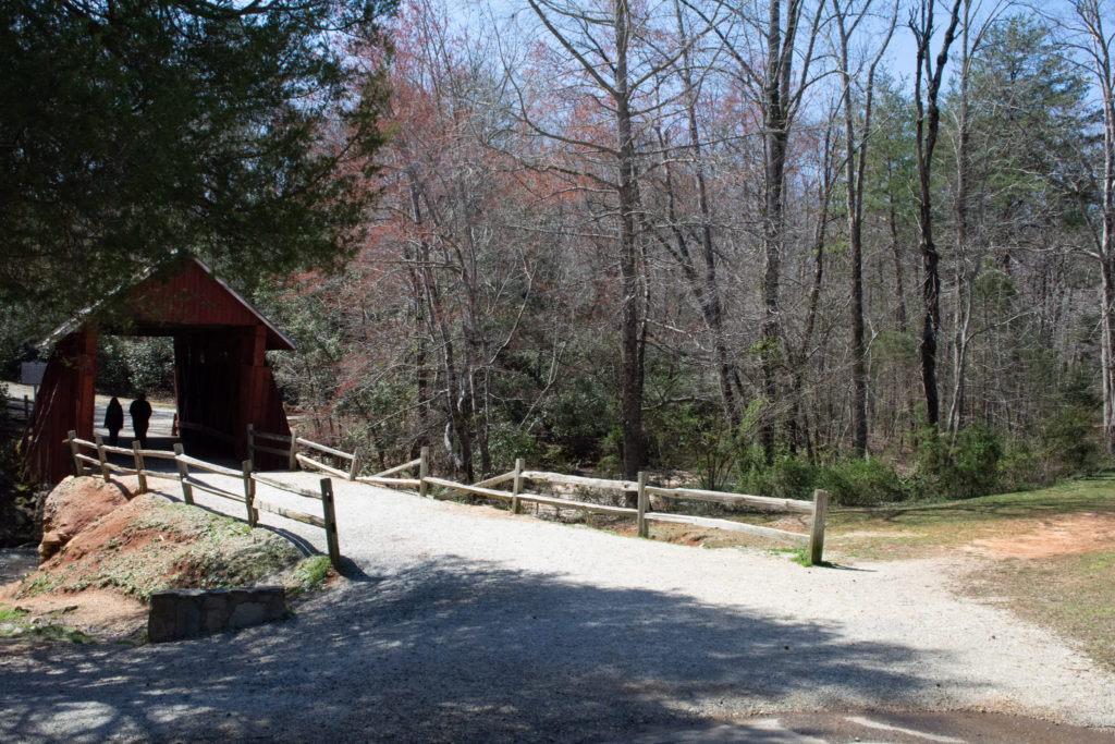 An old covered bridge with 2 people walking through it