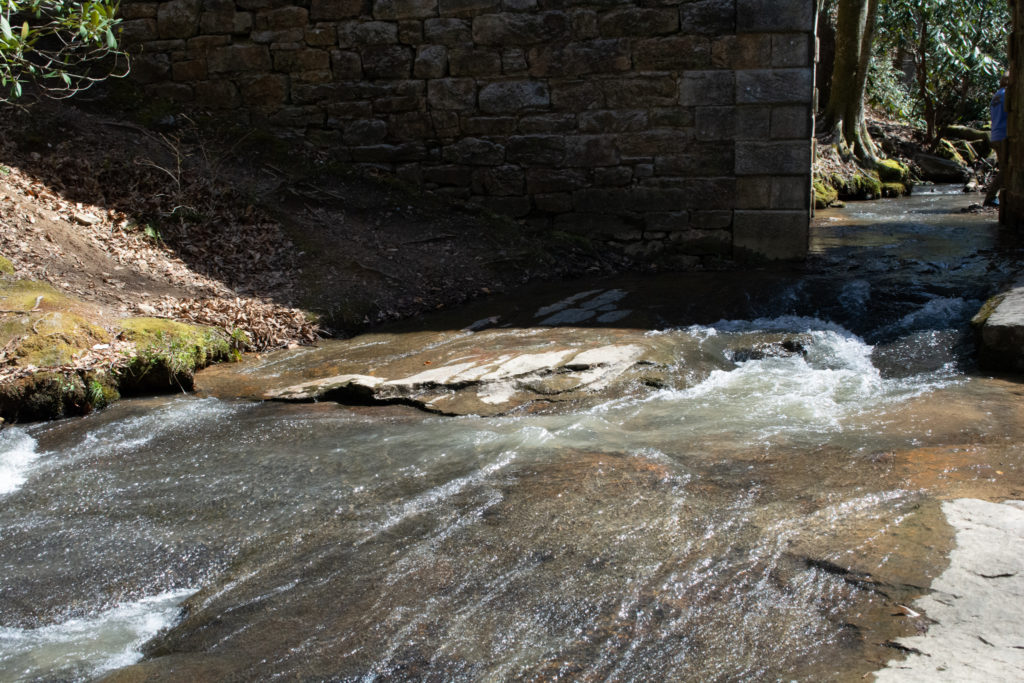 View of a river flowing under an old stone bridge