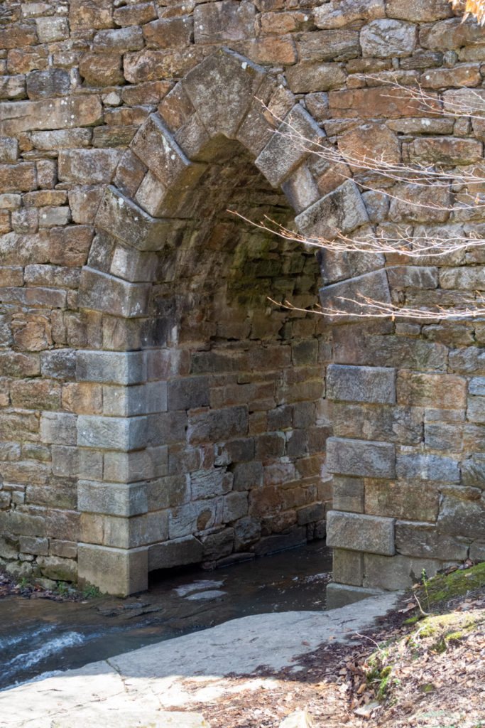 View of the underside of an old stone bridge with the river flowing